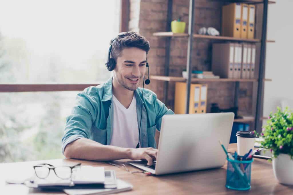 Young smiling experienced operator of call center answering the question of his client